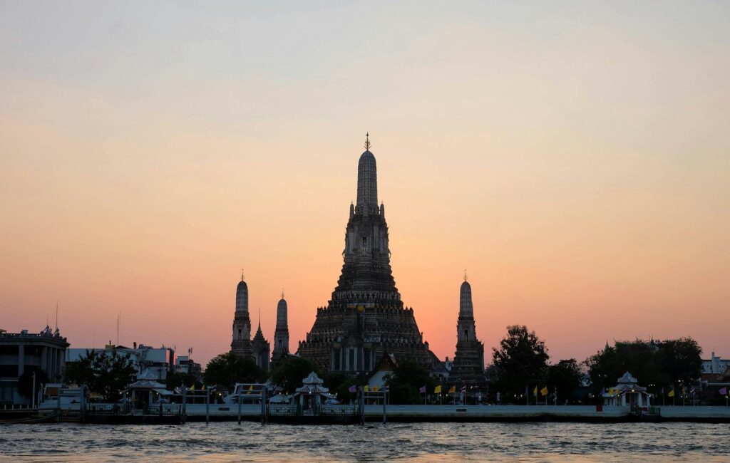 Beautiful sunset view of Wat Arun temple silhouetted against a colorful sky in Bangkok, Thailand.