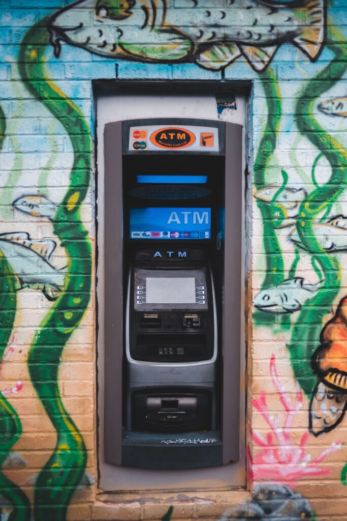 Modern ATM equipment on wall of urban building with bright contemporary street art