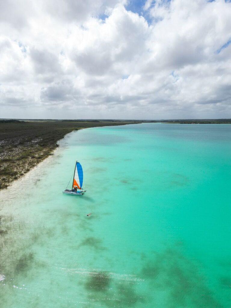 Luftaufnahme eines Katamarans auf der tuerkisen Lagune von Bacalar