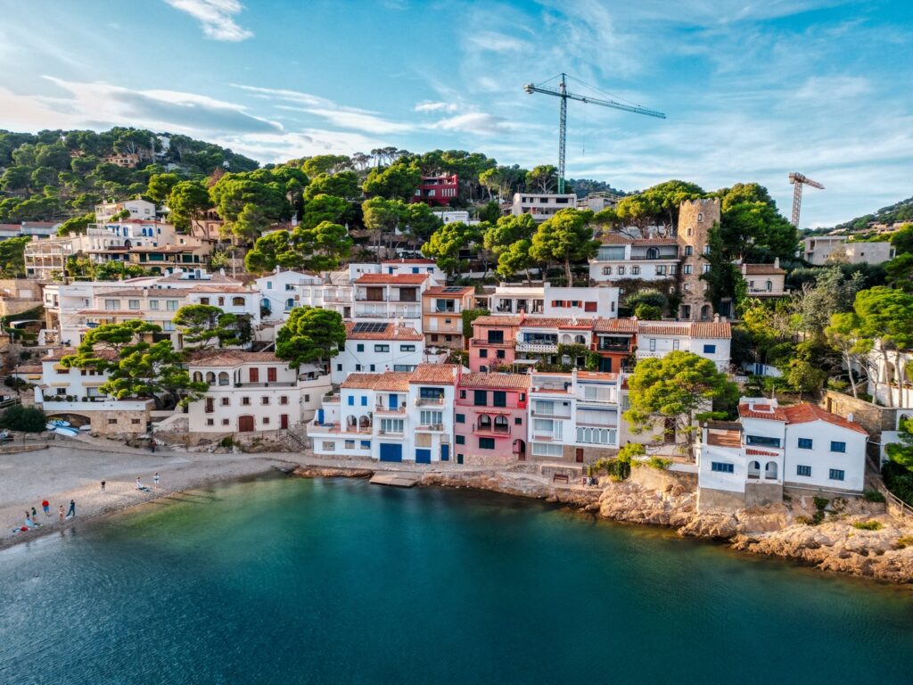Bucht mit buntem Dorf und türkisem Wasser an der Costa Brava