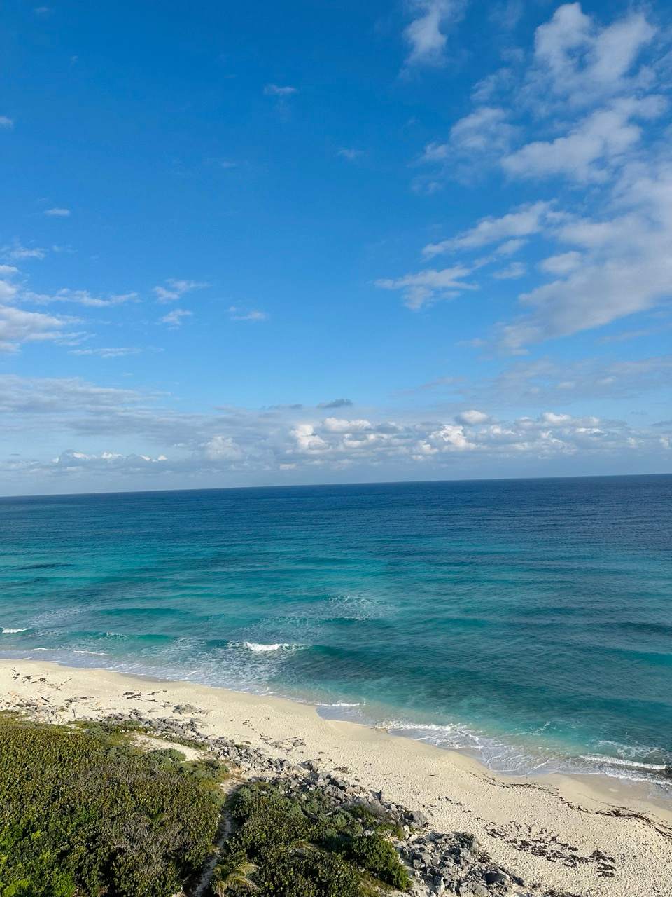 Naturbelassener Strand mit tuerkisem Meer und Felsen an der Kueste von Cozumel