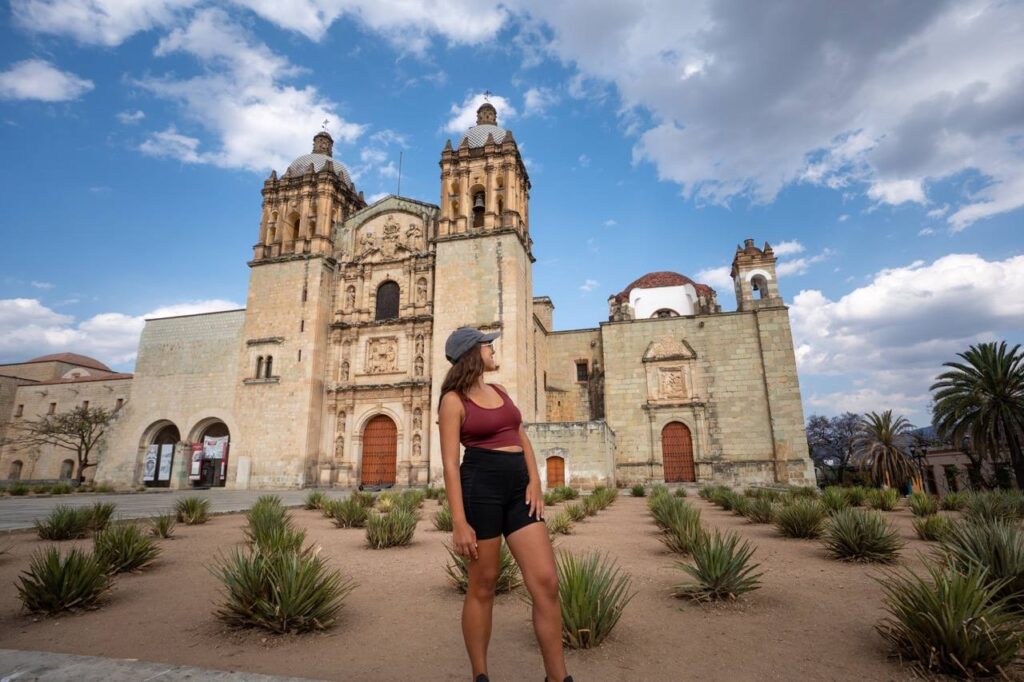 Frau steht im Agavengarten vor der Kirche Santo Domingo in Oaxaca