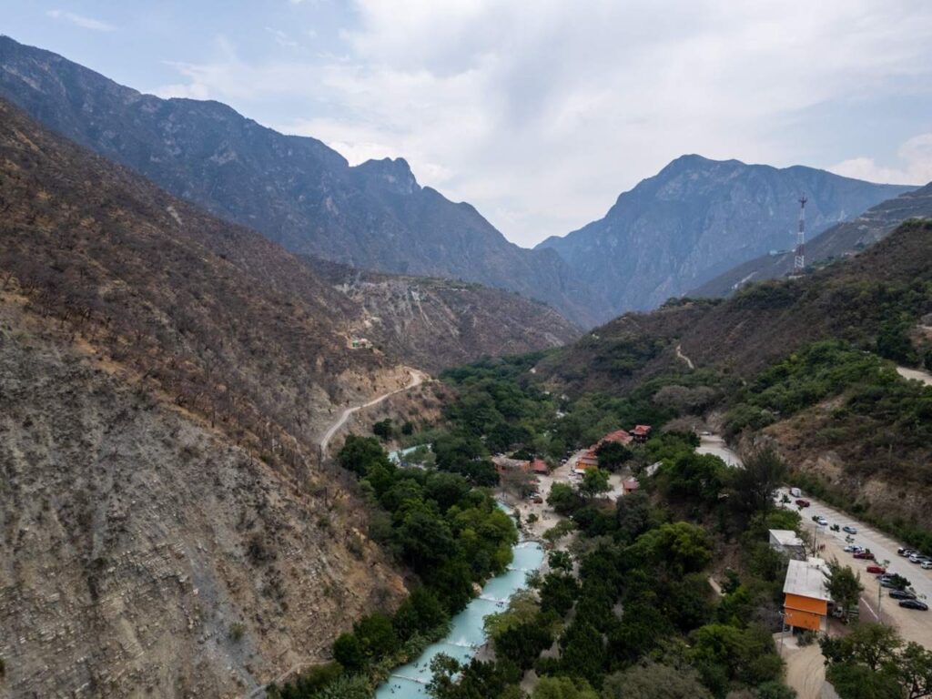 Luftaufnahme des Tals von Grutas de Tolantongo mit tuerkisem Fluss zwischen Bergen