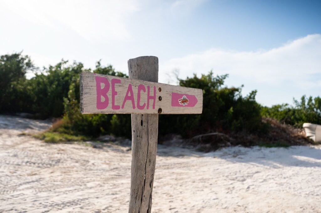 Handbemaltes BEACH-Holzschild im weissen Sand von Holbox zwischen Bueschen