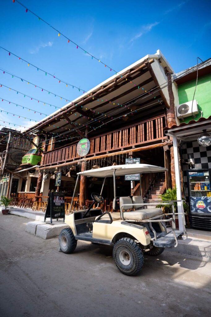Golfcart parkt vor einer Holzbar mit Lichterketten in Holbox