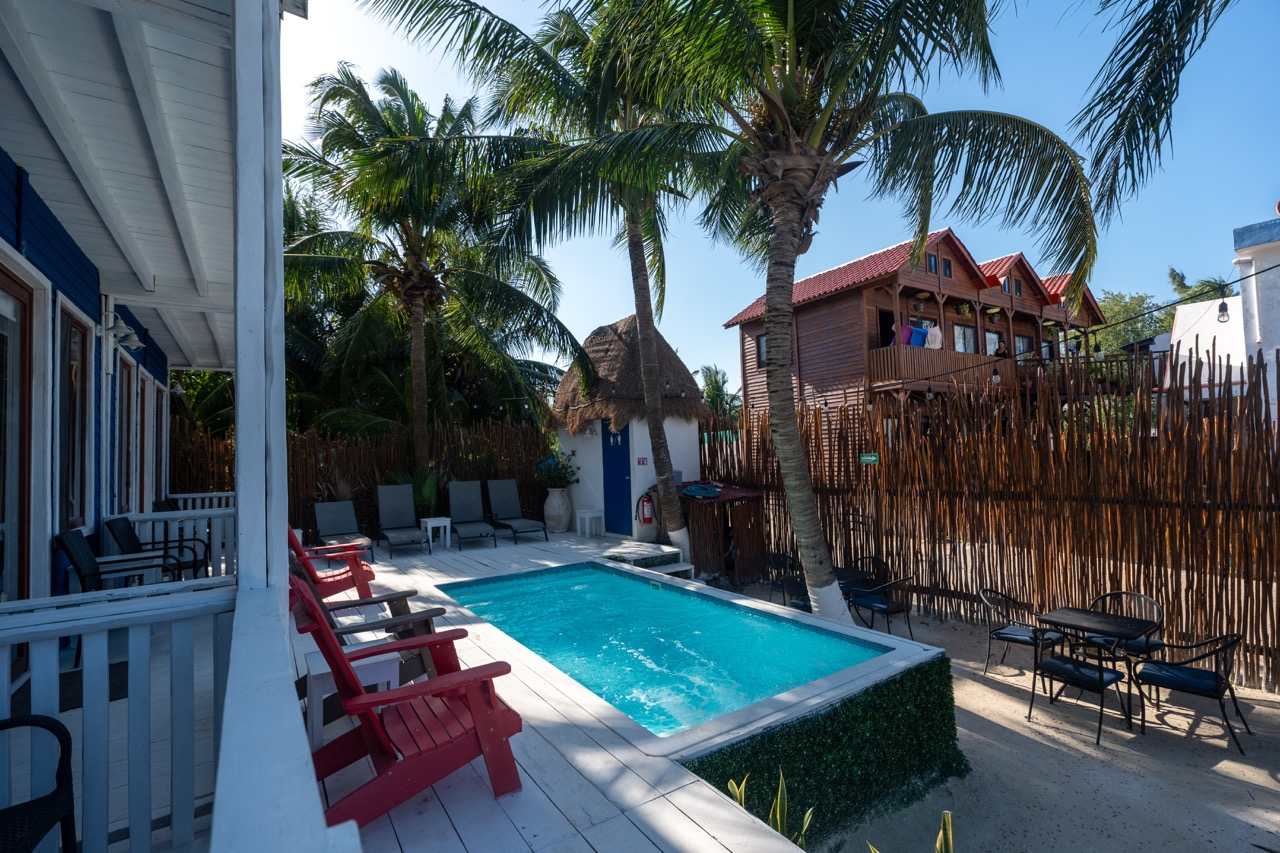 Poolbereich eines Hotels mit Palmen und roten Stühlen auf Holbox