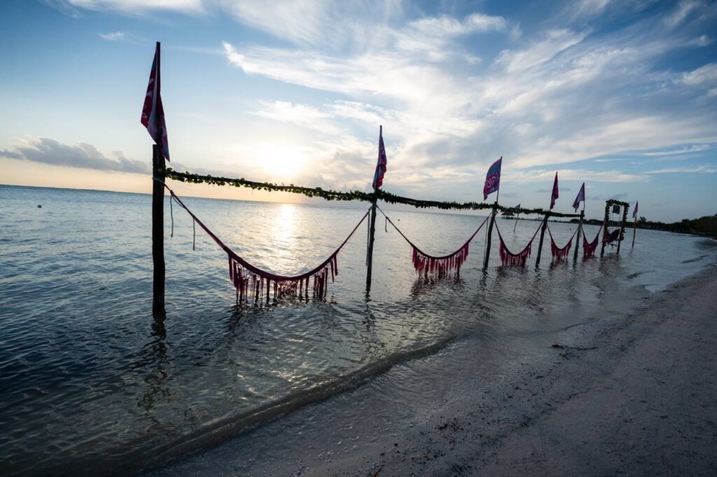 Strand von Holbox bei Sonnenuntergang mit Wimpeln und Deko-Girlanden ueber Wasser