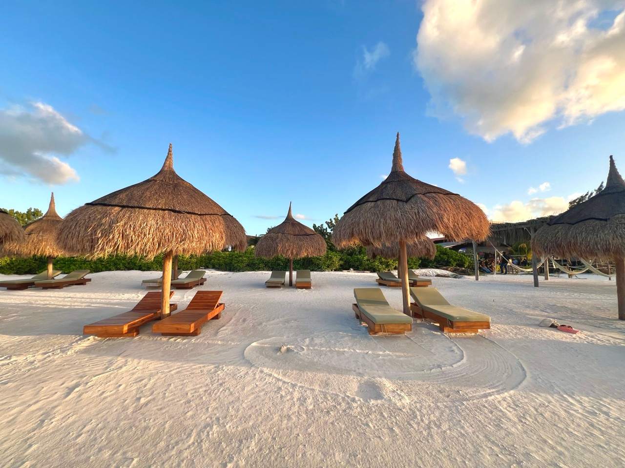 Weisser Strand auf Holbox mit Palapa-Sonnenschirmen, Liegen und Haengematten