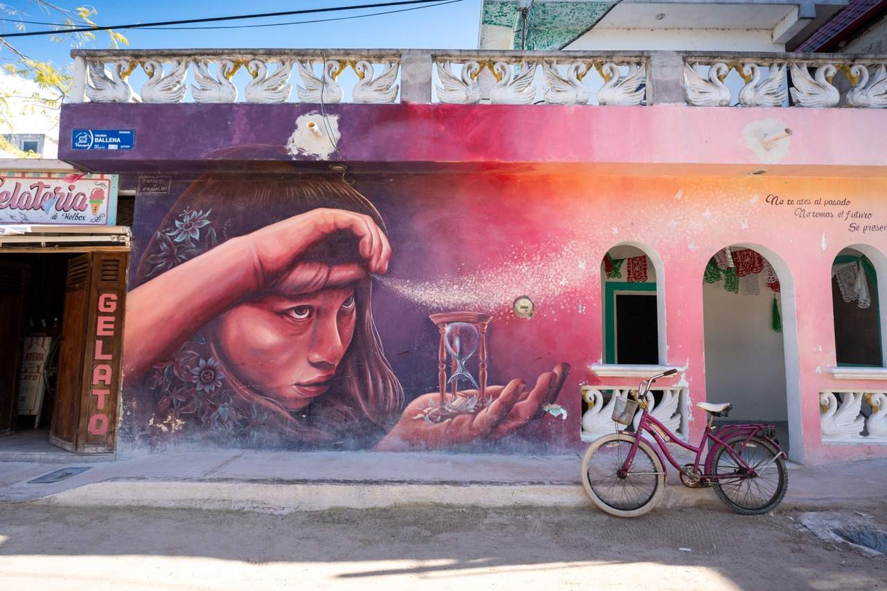 Buntes Streetart-Wandbild an einer Hausfassade in Holbox mit abgestelltem Fahrrad