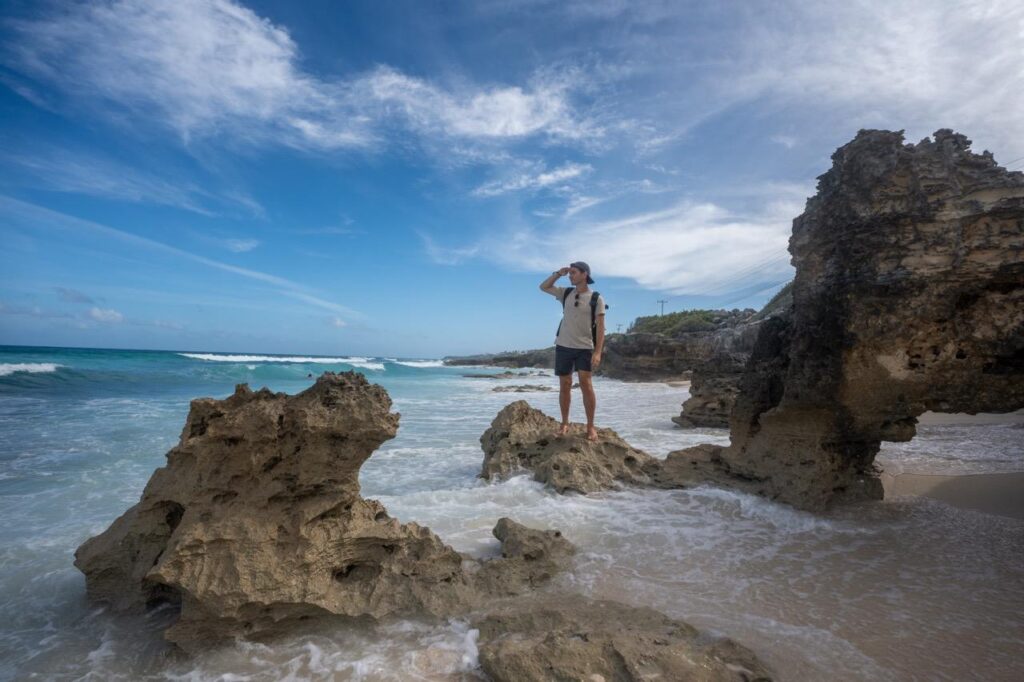 Mann auf Felsen in der Brandung an der Kueste von Isla Mujeres
