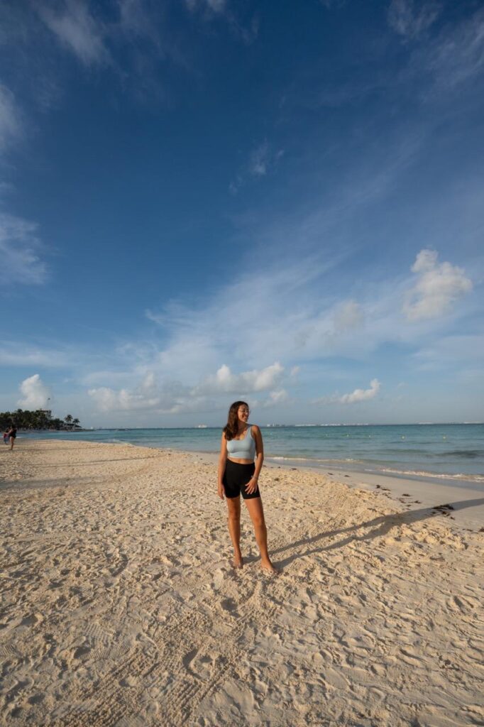 Frau steht am weissen Strand von Isla Mujeres vor tuerkisem Meer