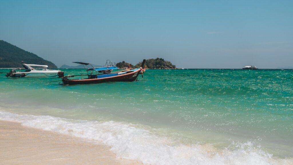 Weißer Strand mit türkisem Wasser und Longtailbooten auf Koh Lipe