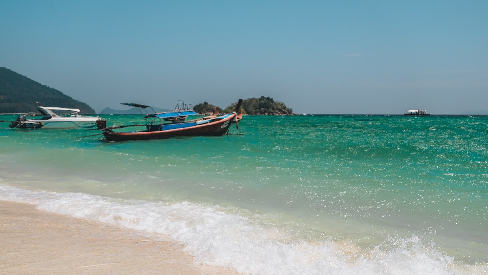 Weißer Strand mit türkisem Wasser und Longtailbooten auf Koh Lipe