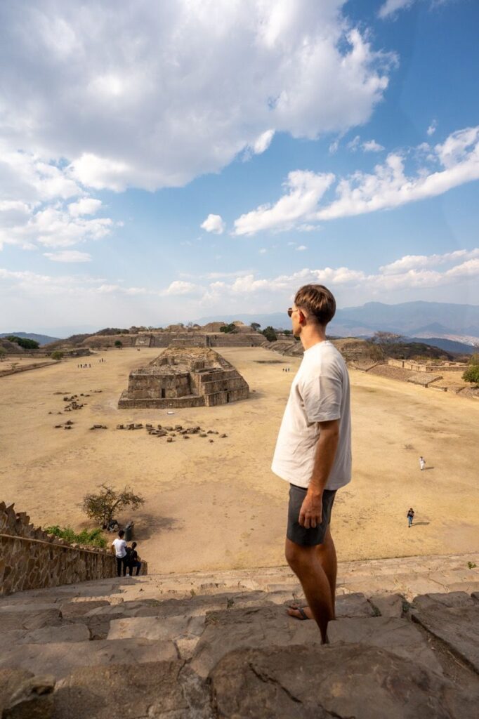 Mann steht auf einer Treppe und blickt ueber den Platz von Monte Alban bei Oaxaca