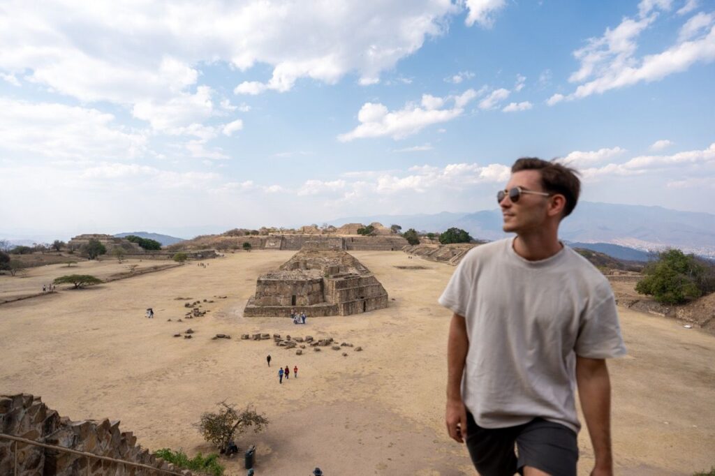 Mann vor dem weiten Platz und den Pyramiden von Monte Alban bei Oaxaca