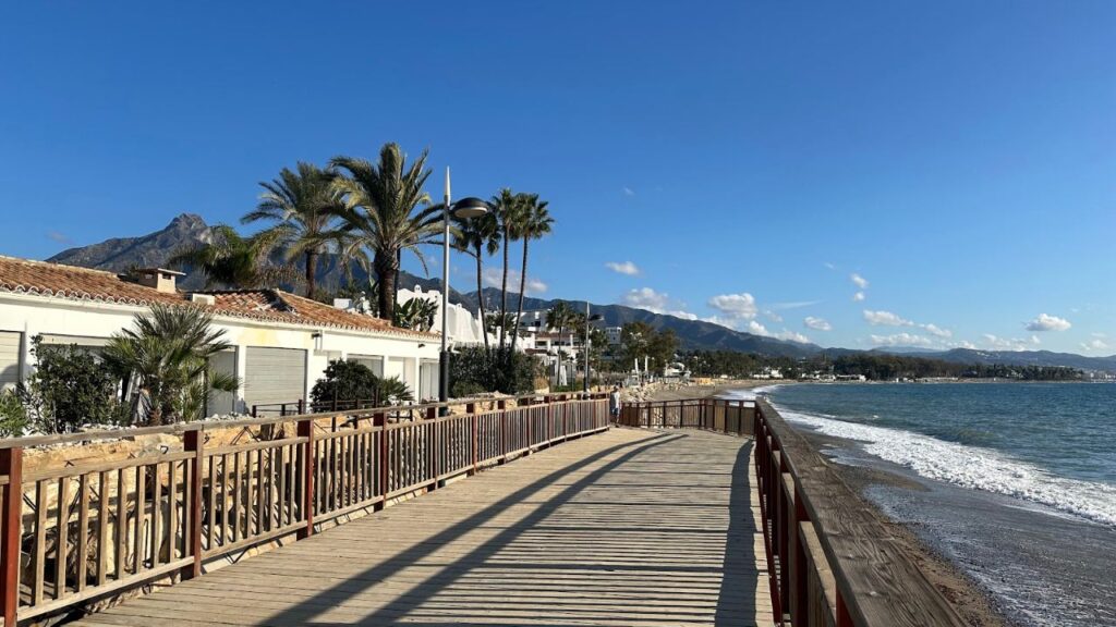 Strandpromenade von Marbella mit Palmen und Bergen