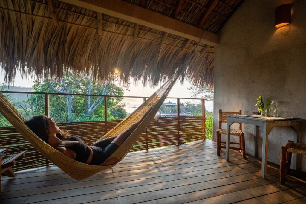 Frau in Hängematte auf Palapa-Terrasse bei Sonnenuntergang in Mazunte