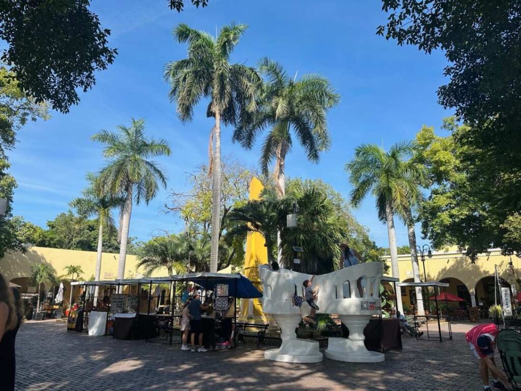 Grosse weisse Confidente-Stuehle auf einem Platz mit Palmen in Merida