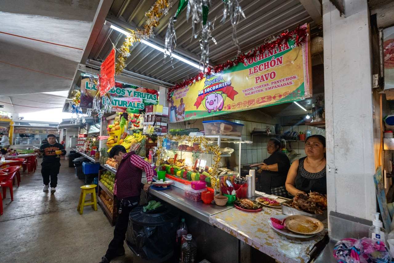 Taqueria-Stand mit Speisen auf einem ueberdachten Markt in Merida