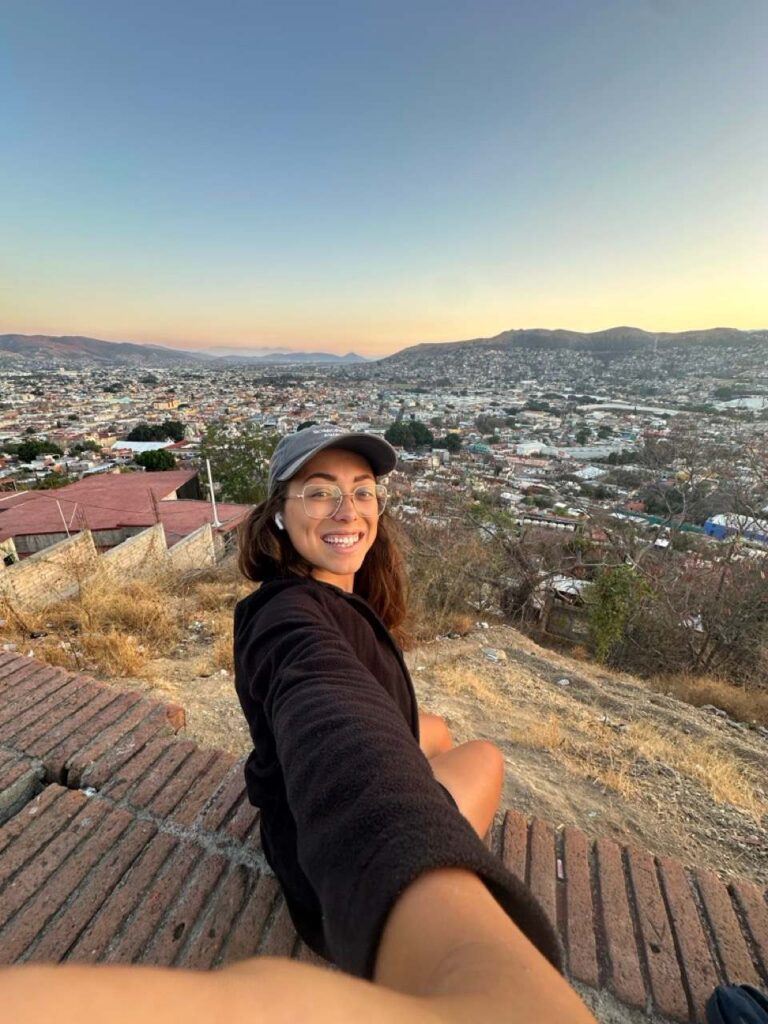 Frau blickt bei Sonnenuntergang ueber die Stadt Oaxaca