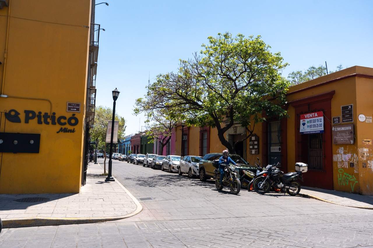 Bunte Kolonialgasse in Oaxaca mit gelber Hauswand und geparkten Motorraedern