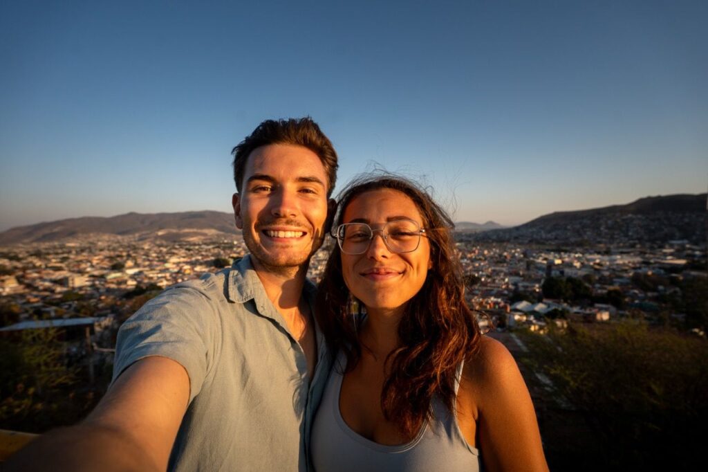 Paar-Selfie an einem Aussichtspunkt ueber Oaxaca im Abendlicht