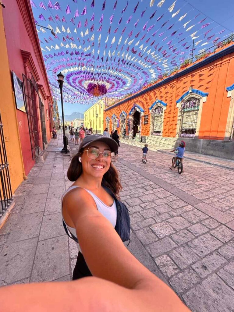 Selfie einer Frau unter Papel-Picado-Wimpeln in einer Kolonialgasse in Oaxaca