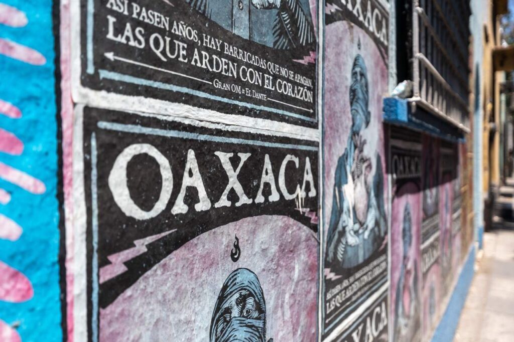 Streetart-Plakate mit dem Schriftzug Oaxaca an einer Wand in Oaxaca