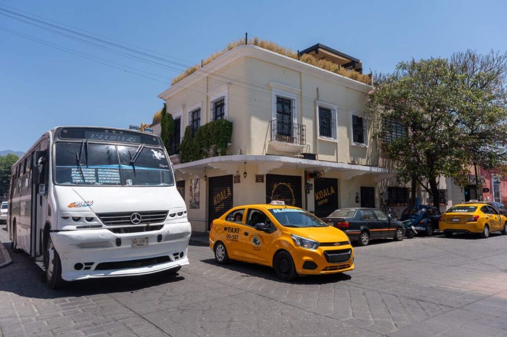 Gelbes Taxi und Bus an einer Strassenecke in der Altstadt von Oaxaca