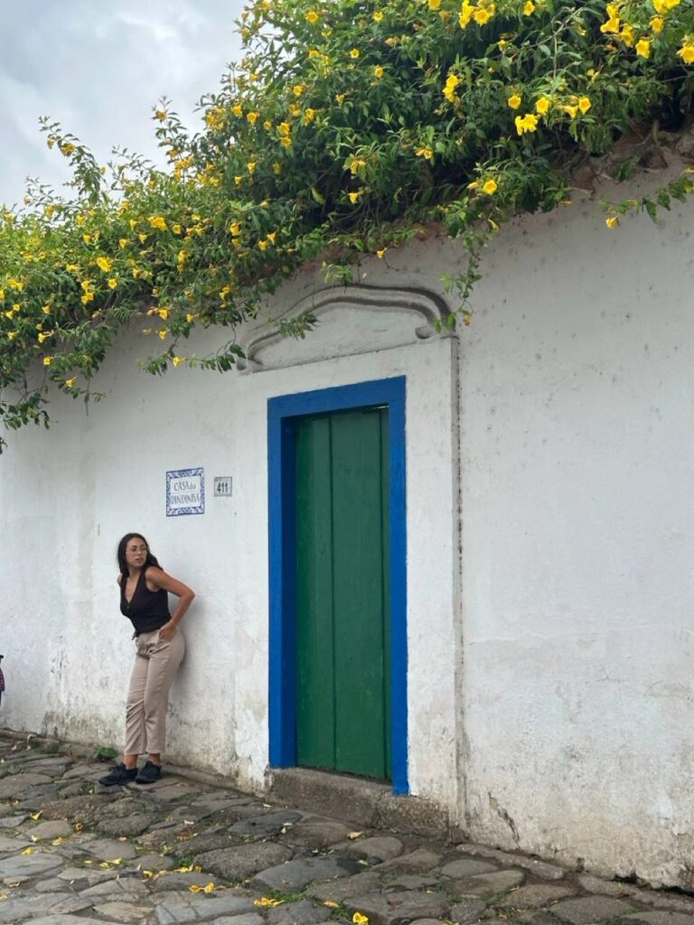 Frau an einer weißen Hauswand mit grüner Tür in Paraty