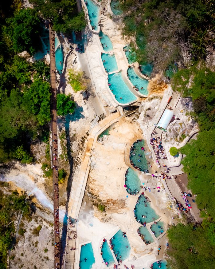 Stunning aerial view of turquoise thermal pools at Grutas Tolantongo, Mexico, surrounded by lush greenery.