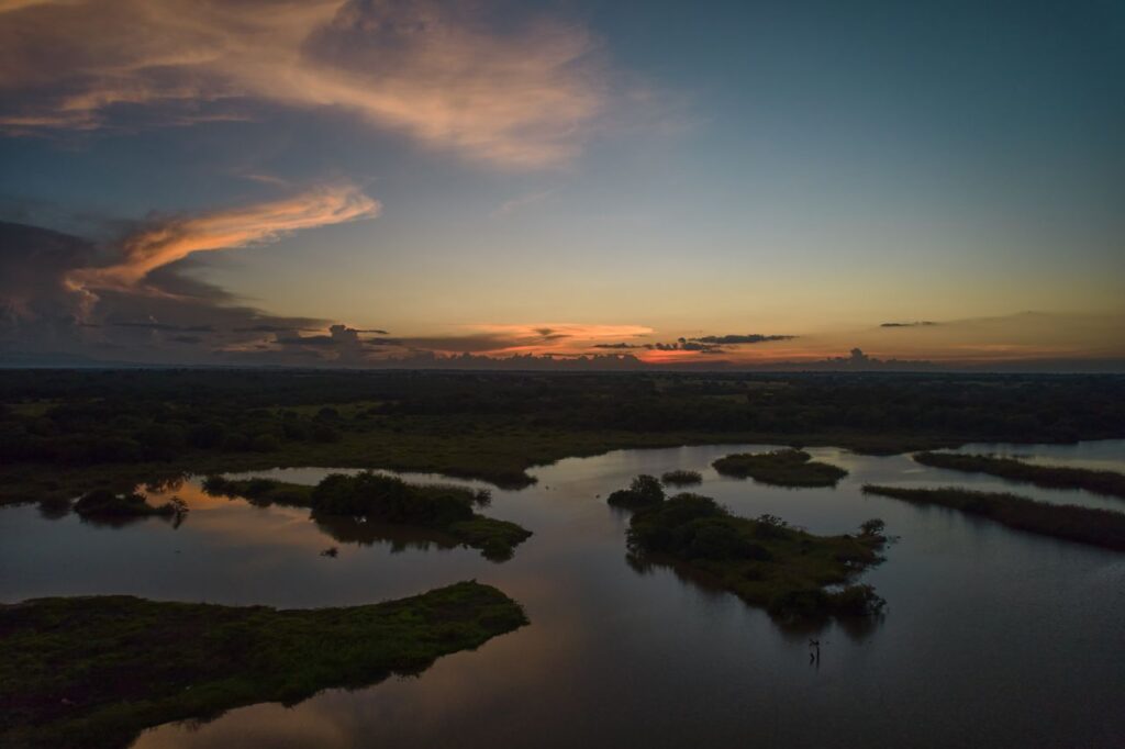 A peaceful sunset scene over Catazajá, Mexico, featuring calm waters and a dramatic sky.