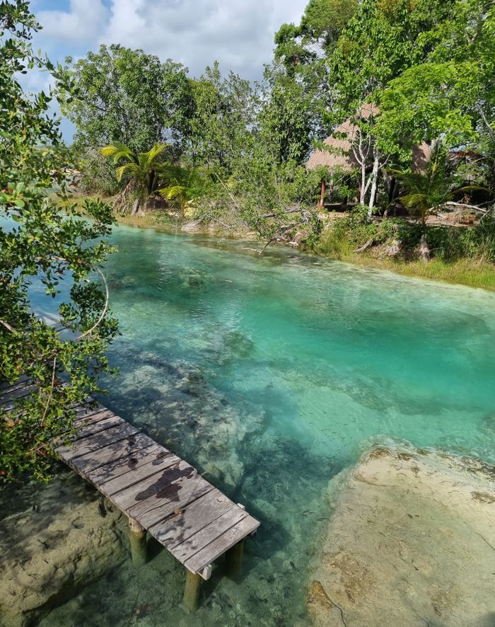 Explore the clear turquoise waters by a wooden pier in Bacalar, Mexico.
