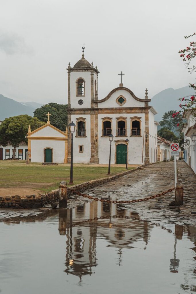 Reflection of a historic church in Paraty, Brazil, on a wet cobblestone street.