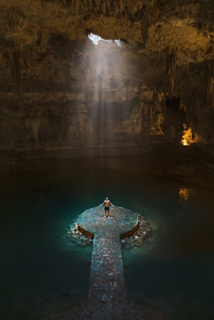 Explore a breathtaking cenote with sunrays filtering through limestone formations in Cancún.