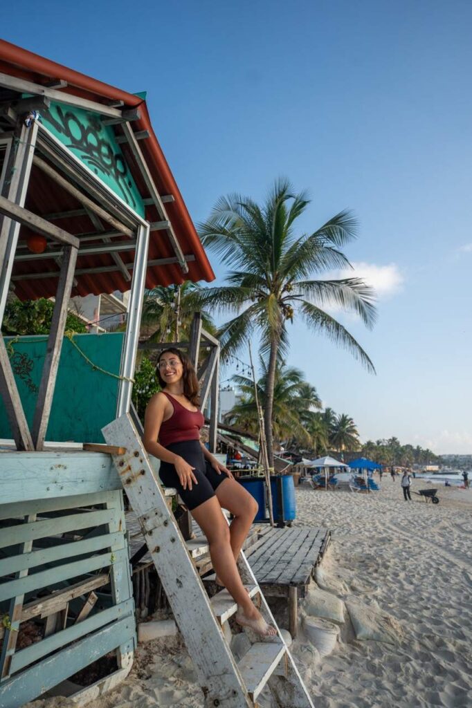 Frau an der Treppe einer Strandbar mit Palmen in Playa del Carmen