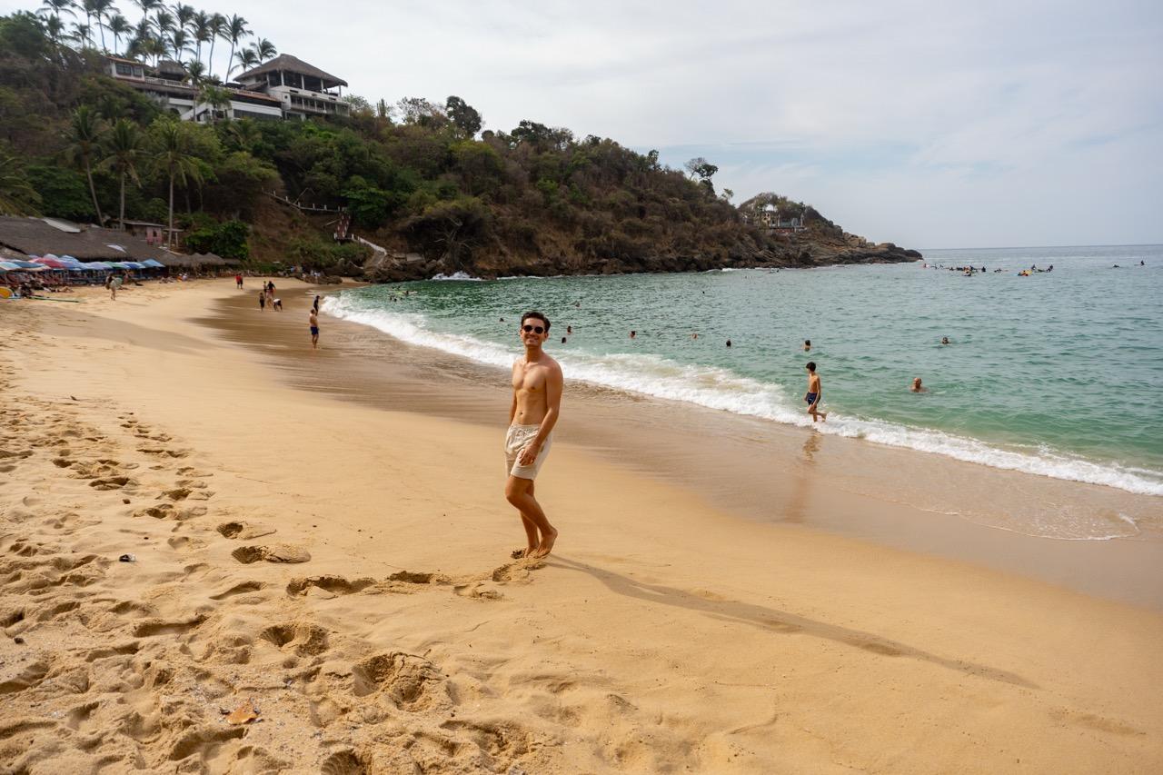 Mann an einer Bucht mit tuerkisem Wasser in Puerto Escondido