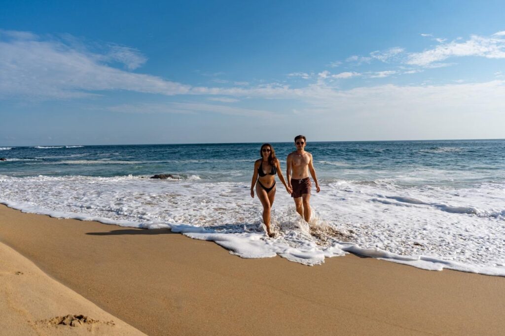 Paar laeuft Hand in Hand durch die Brandung in Puerto Escondido