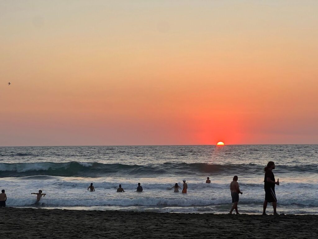 Badende in den Wellen bei Sonnenuntergang am Strand von Puerto Escondido