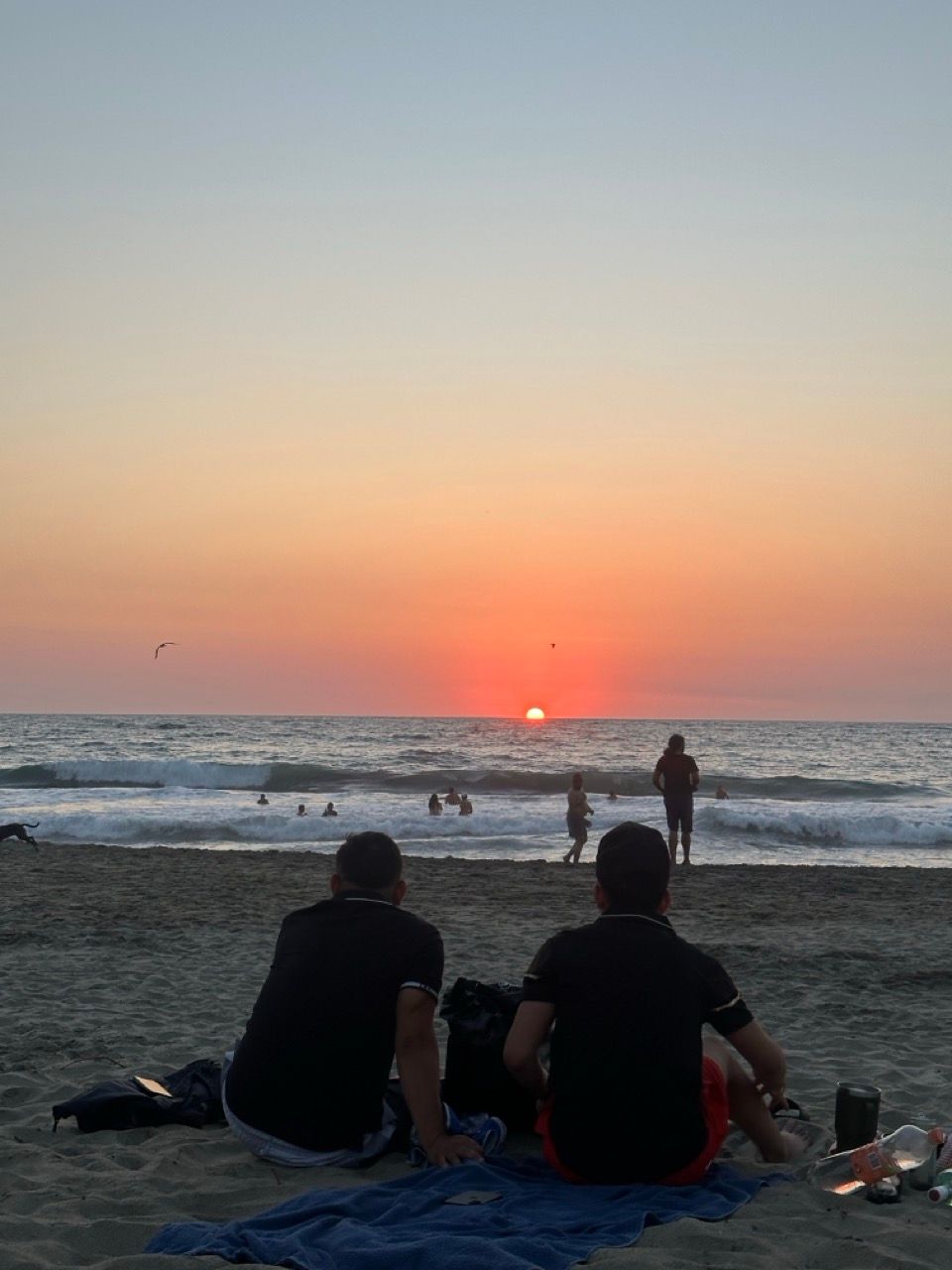 Zwei Maenner sitzen am Strand von Puerto Escondido und schauen auf den Sonnenuntergang
