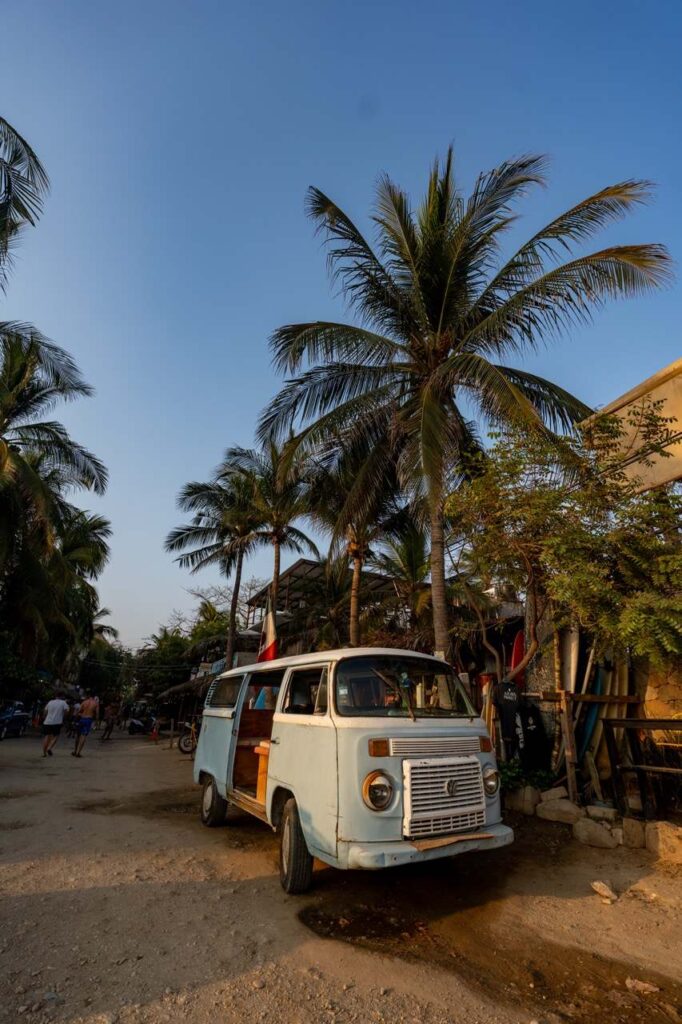 Alter VW-Bus unter Palmen an einer Sandstrasse in Puerto Escondido