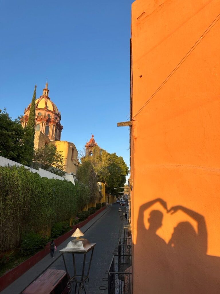 Kirchenkuppel und ein Herzschatten an einer orangen Wand in San Miguel de Allende