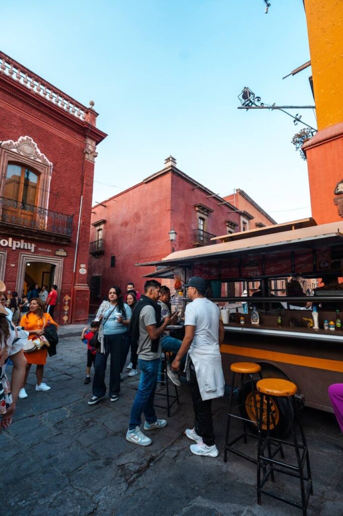 Menschen am Taco-Stand vor bunten Kolonialhaeusern in San Miguel de Allende