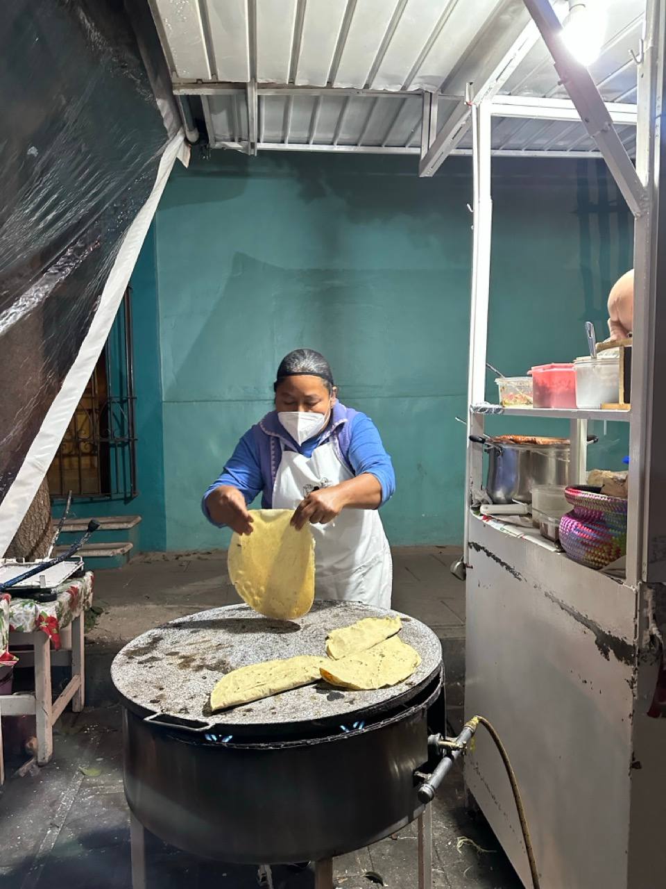 Frau backt frische Tortillas auf dem Comal an einem Streetfood-Stand in Oaxaca
