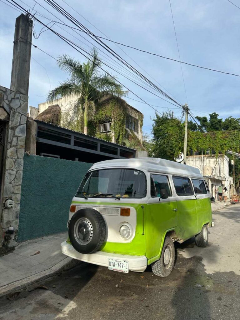 Gruener alter VW-Bulli parkt an einer Strasse in Tulum
