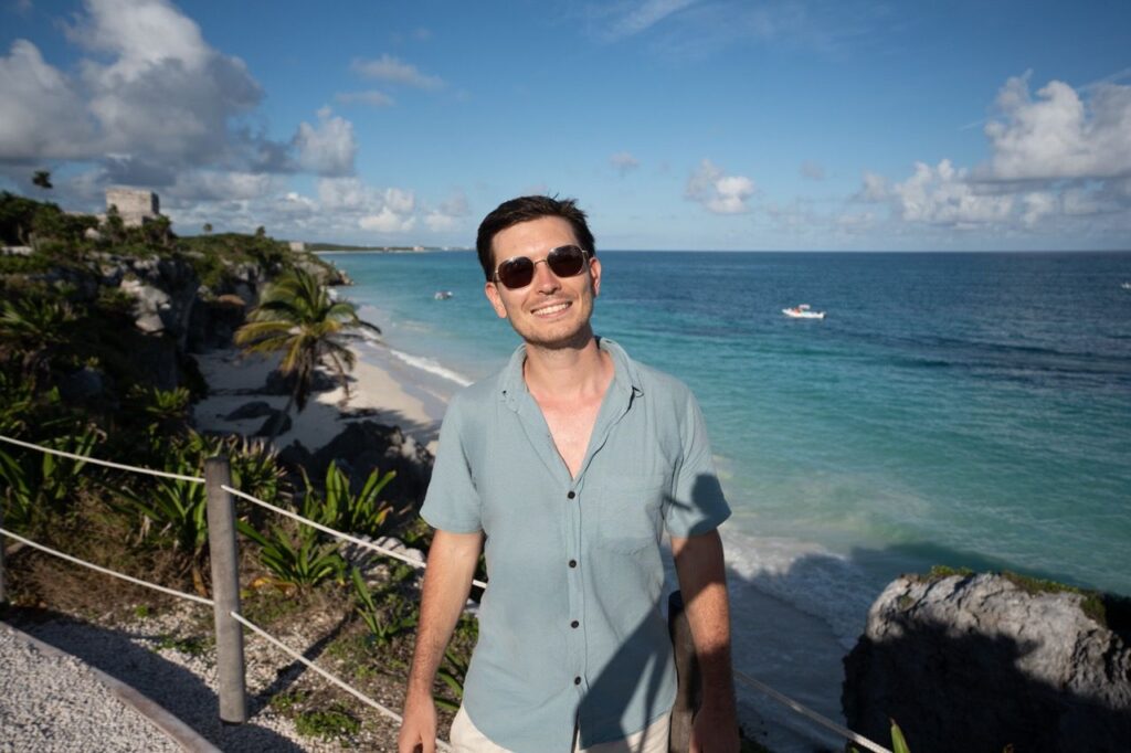 Portrait eines Mannes am Ruinenstrand von Tulum mit tuerkisem Meer