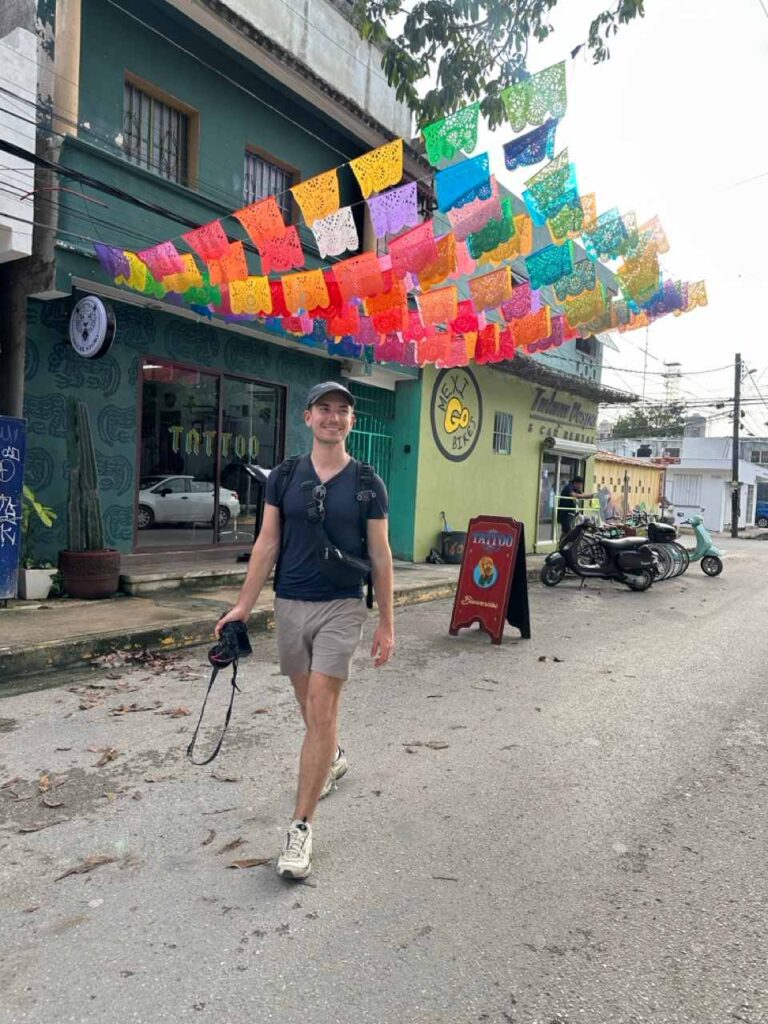 Bunte Strasse in Tulum mit Papel-Picado-Girlanden und Person mit Kamera