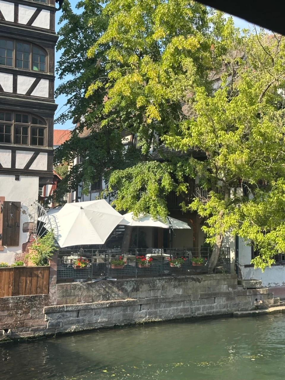 Restaurantterrasse am Kanal in Strassburg unter Baeumen