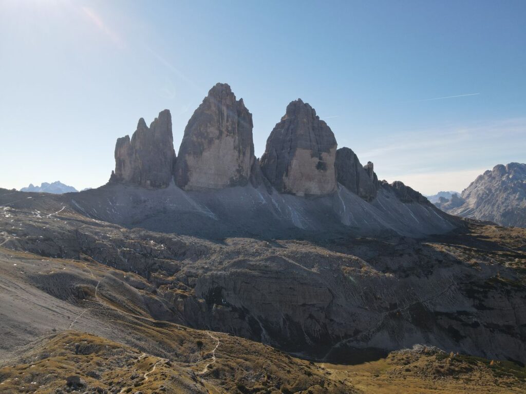 Stunning aerial shot of Tre Cime di Lavaredo in the Italian Alps, showcasing majestic mountain peaks under clear skies.