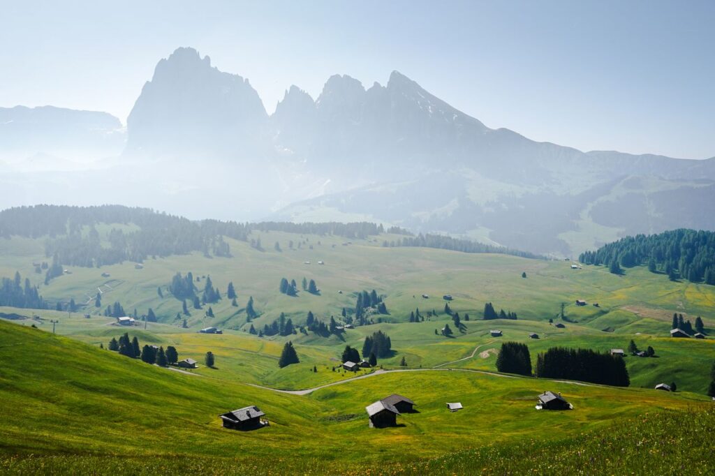 Panorama der Dolomiten mit grünen Almwiesen und Berghütten
